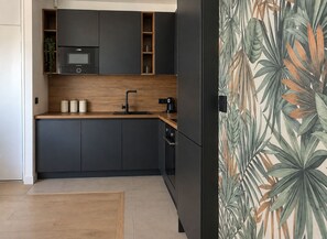 Una cocina moderna con armarios oscuros, encimera de madera y microondas integrado.