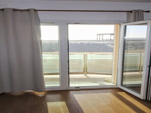 Ein Zimmer mit einer großen Schiebeglasdoor zum Balkon mit Meerblick.
