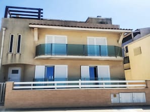 Ein mehrstöckiges Gebäude mit Balkon, Fenstern und einer Tür.