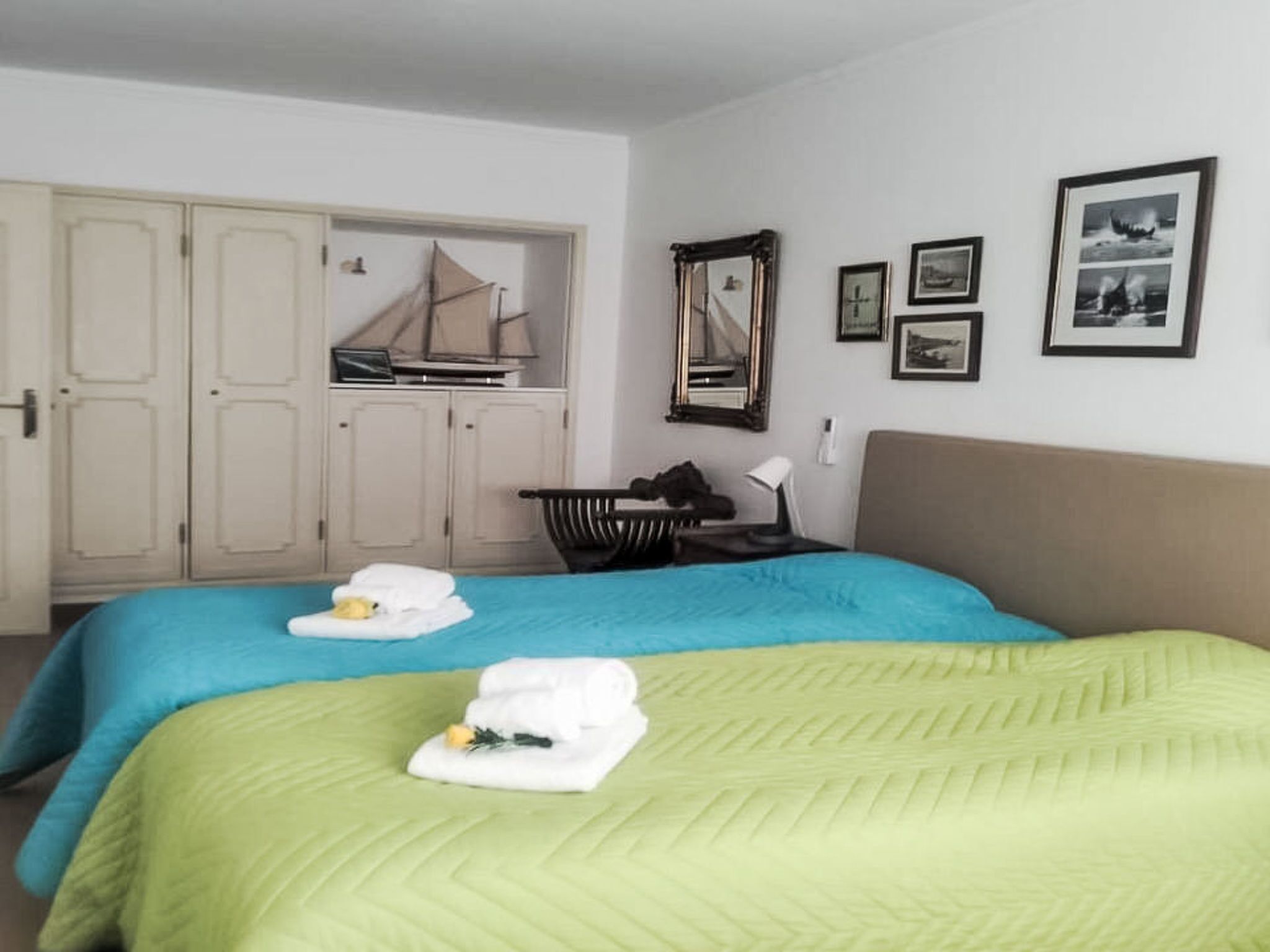 Habitación de hotel con cama, armario, escritorio y espejo.
