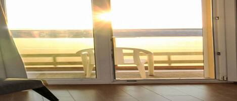 Una habitación con un gran ventanal corredero que da a un balcón con vistas al mar.