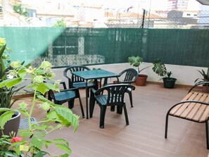 A patio with a table and chairs, potted plants, and a green fence. - Aveiro Apartment with Patio by Interhome (Aveiro)