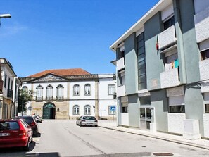 A street view with a building featuring a classical facade, a red car parked on the side, and a clear blue sky. - Aveiro Apartment with Patio by Interhome (Aveiro)