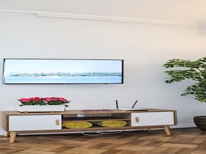 A modern living room with a flat-screen TV mounted on the wall, a wooden console table with drawers, a potted plant, and a large green plant. - Aveiro Apartment with Patio by Interhome (Aveiro)