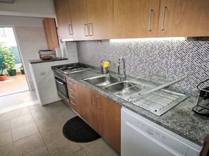 Une cuisine avec des meubles en bois, un plan de travail en granit, un évier en acier inoxydable et un lave-vaisselle.