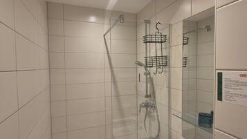 A modern bathroom with a glass shower enclosure, a white sink, and a mirror with a sign.