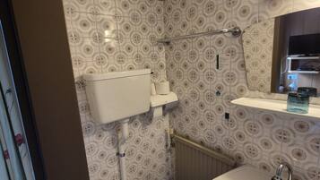 Un baño con inodoro, lavamanos y zona de ducha.