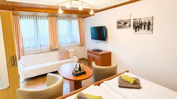 Habitación de hotel con cama, sofá, una mesita y televisión.