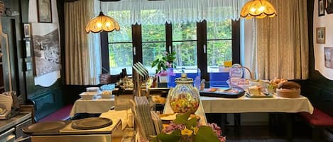 A dining area with a table set for a meal, a coffee machine, and a window with curtains.