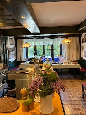 A dining area with a table set for a meal, a coffee machine, and a window with curtains.