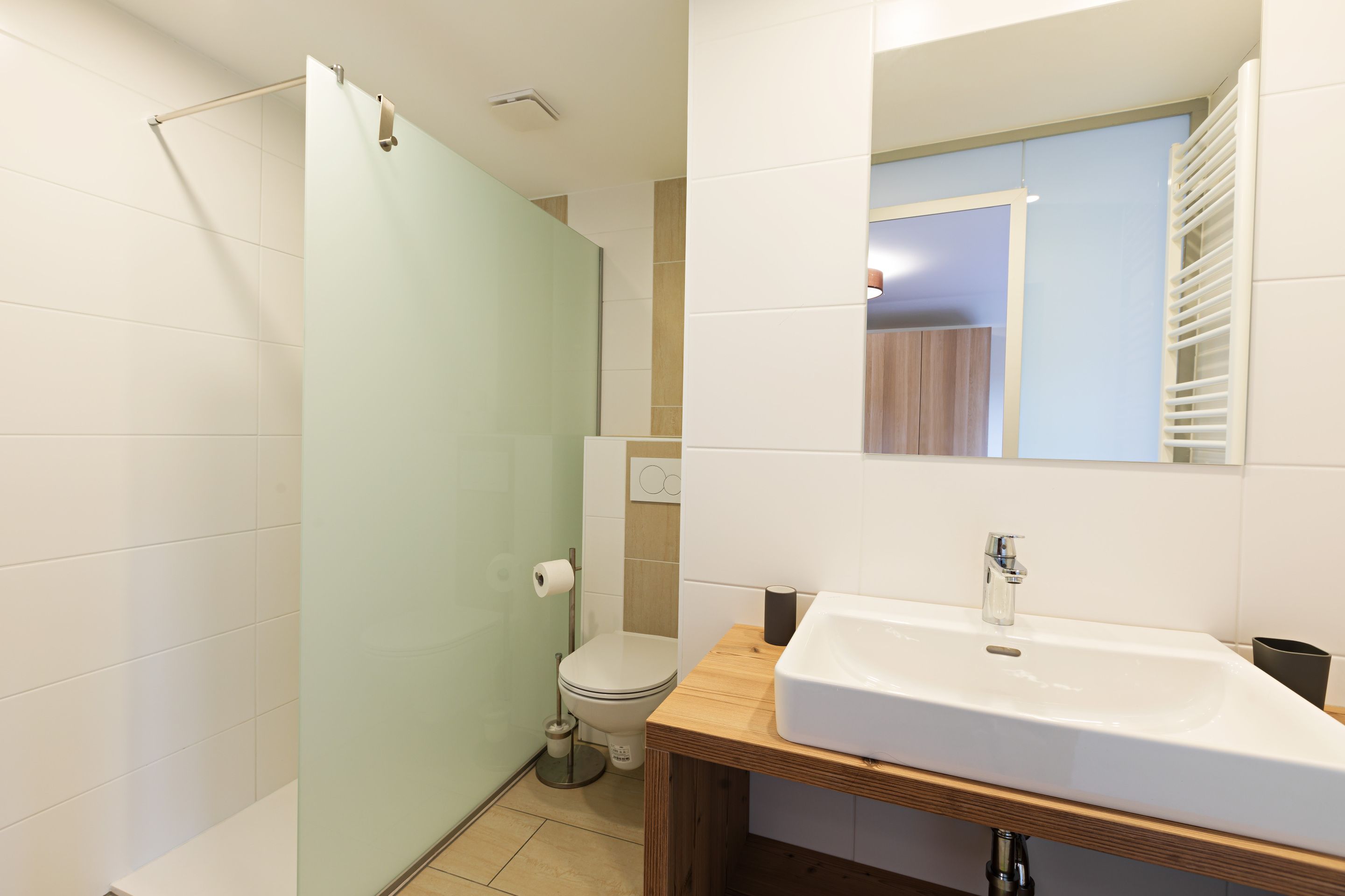 A modern bathroom with a shower, toilet, and sink.
