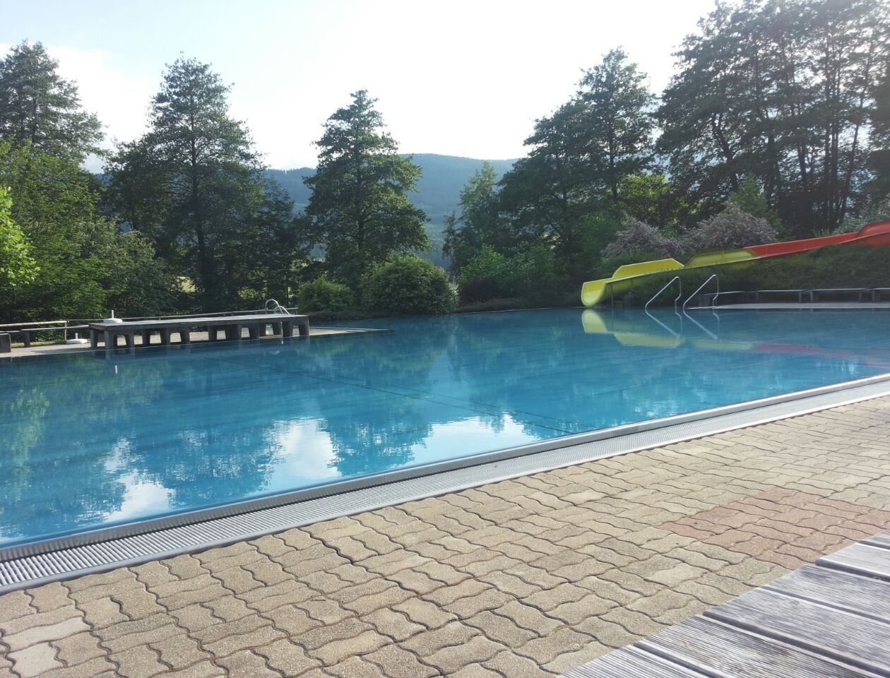 A swimming pool with a clear view of the surrounding landscape, including trees and distant hills.