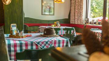 A restaurant interior with checkered tablecloths, a hat on a table, and a hanging light fixture.