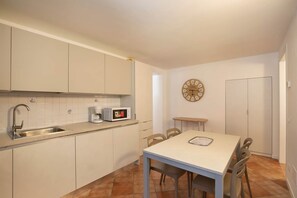 A compact kitchen with a sink, coffee maker, microwave, and a clock on the wall. - Casa Gloria - in the center of San Zeno di Montagna (San Zeno di Montagna)