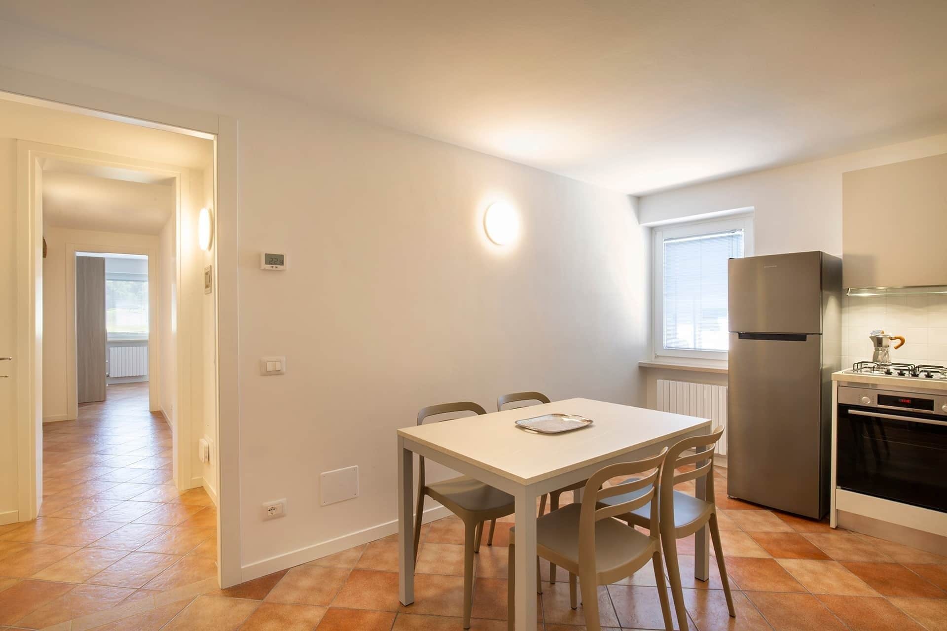 Eine kleine Küche mit Esstisch, Stühlen, Kühlschrank und Herd.