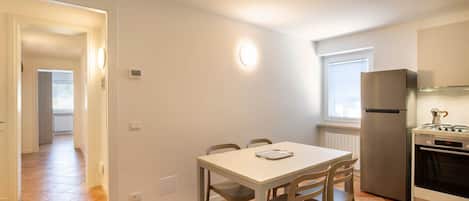 Eine kleine Küche mit Esstisch, Stühlen, Kühlschrank und Herd.