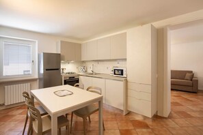 Eine kleine Küche mit Esstisch, Stühlen, Kühlschrank, Herd und Mikrowelle.