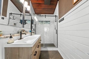Ein modernes Badezimmer mit einer weißen Duschkabine, einem Waschbecken mit Holzunterschrank und einer Glaskabinentür.