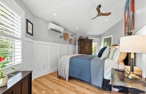 Ein Schlafzimmer mit Bett, Nachttisch, Lampe und Deckenventilator.
