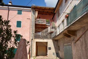 Eine enge Gasse mit einem Gebäude, das eine Holztreppe und einen Balkon besitzt.