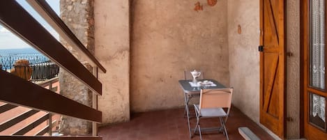 Un balcón con mesa y sillas, una puerta de madera y vistas al mar.