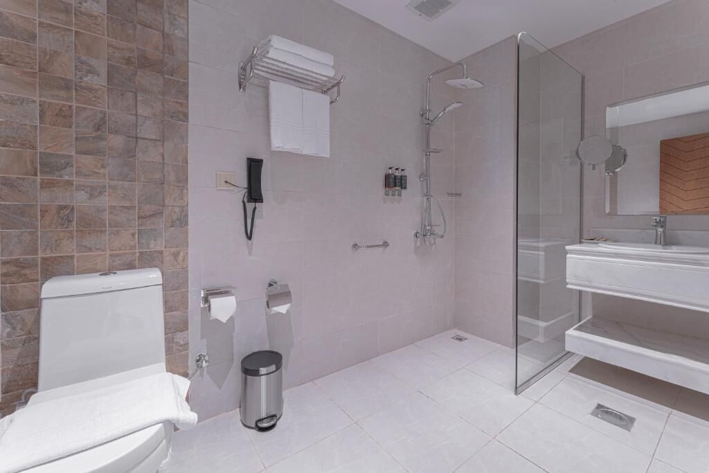 A modern bathroom with a toilet, a glass-enclosed shower, and a vanity with a mirror.