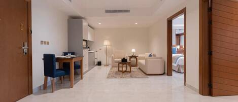 A modern hotel room with a dining area, a sofa, a lamp, and a bed.