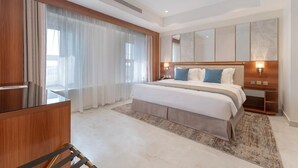 A modern hotel room with a large bed, a desk, and a large window with curtains. - Corp Yanbu Hotel B1 (Yanbu)