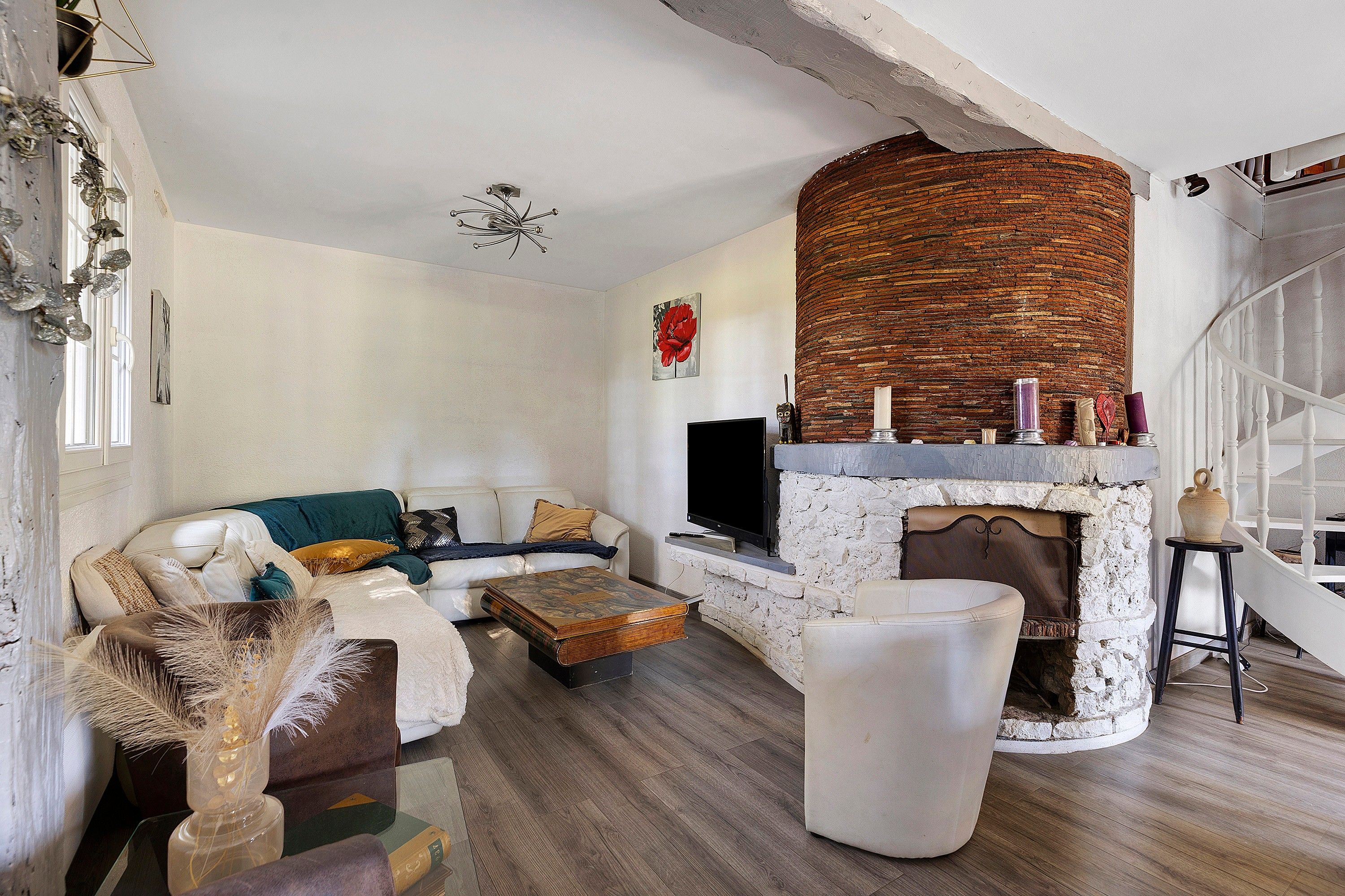 Un salon avec une cheminée en pierre, un canapé, une table basse et un téléviseur.