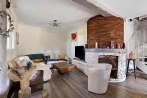 A living room with a stone fireplace, a sofa, a coffee table, and a television.