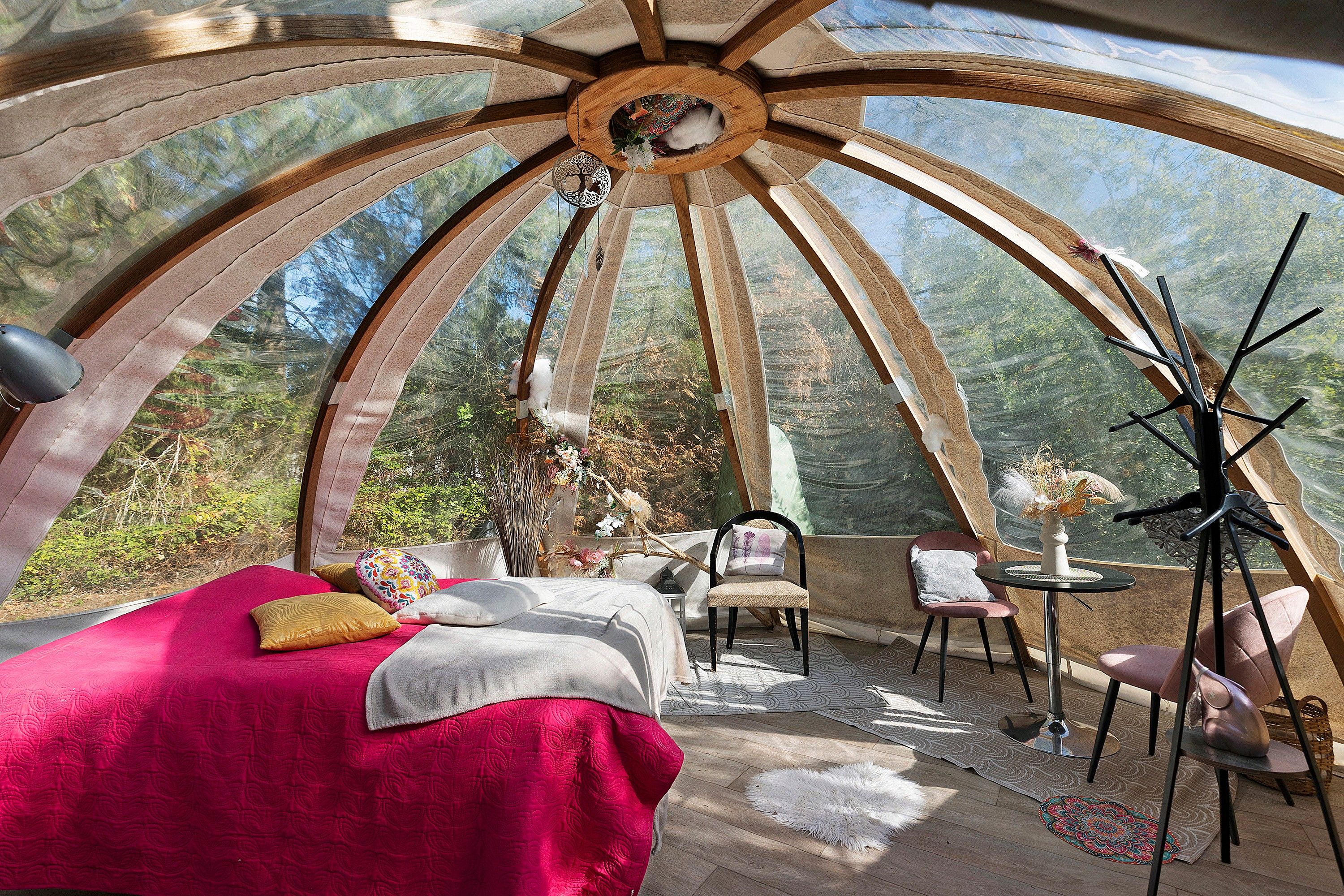 A dome-shaped room with a bed, chairs, a table, and a hanging light fixture.