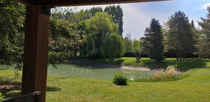 Ein ruhiger Außenbereich mit Teich, Bäumen und einer Holzkonstruktion.
