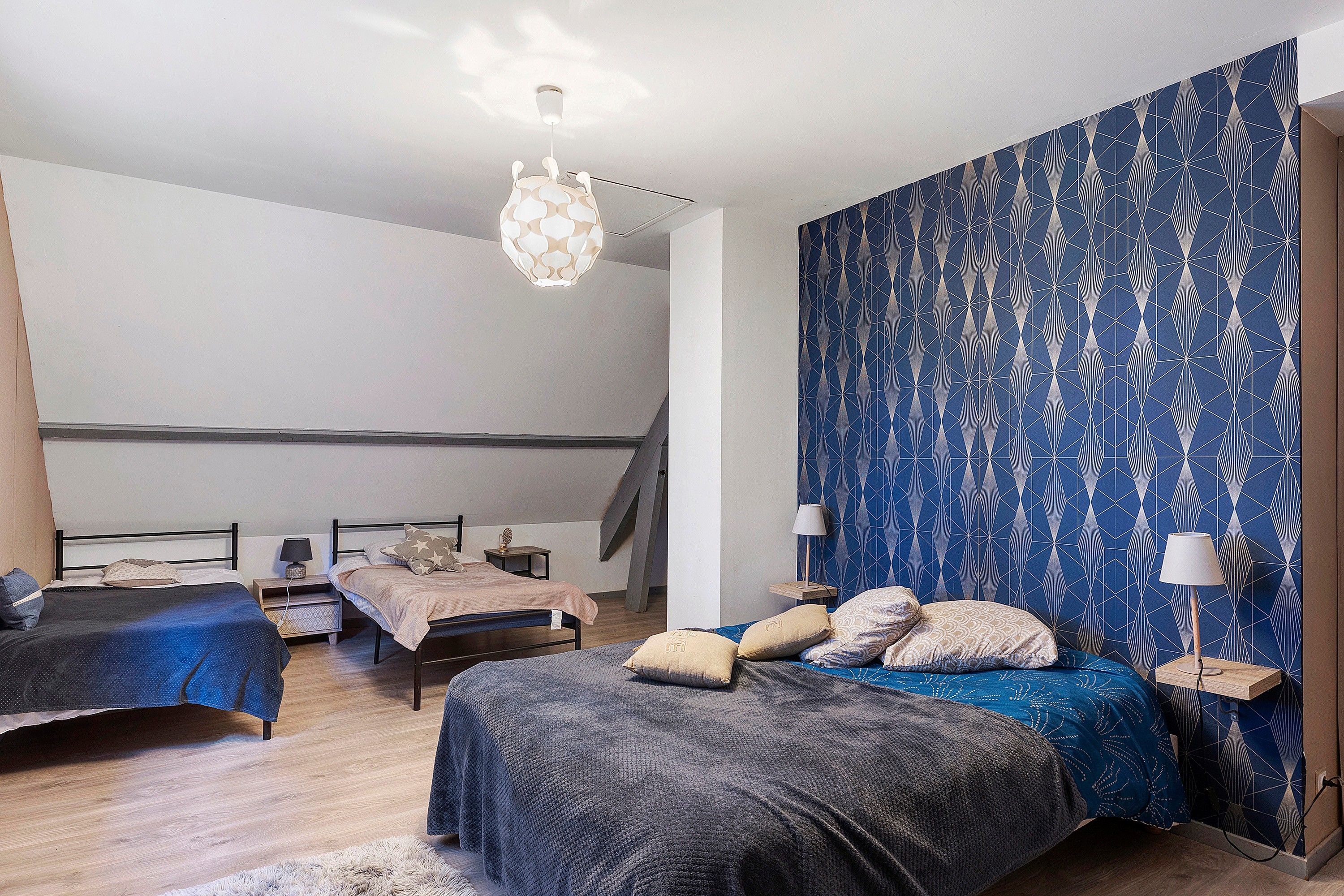 Une chambre avec deux lits, un escalier et un mur orné d’un motif.