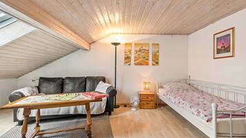 Een kamer met een stapelbed, een slaapbank, een tafel met een spel, een lamp en een foto van de Eiffeltoren.