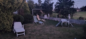 Puutarha, jossa on ulkotilaa istumiseen, pergola ja patsaita.