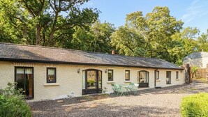 A single-story building with a gravel driveway and a small patio area. - The Coach House Cottage (Dromineer)