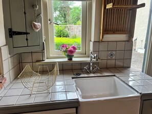 A kitchen with a window, a sink, and a vase with flowers. - The Coach House Cottage (Dromineer)