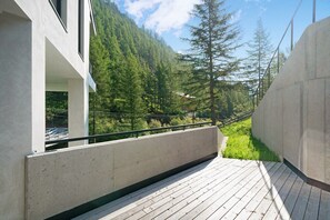 En træterrasse med udsigt over et skovklædt bjerrelandskab.
