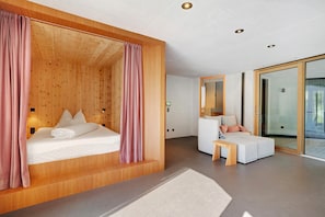 Una habitación de hotel moderna con una pared decorada con madera, una cama, un sofá, una mesita y un ventanal de vidrio que da a un balcón.