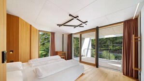 Une chambre d’hôtel moderne avec un grand lit, un plancher en bois, un luminaire au plafond et une vue sur un balcon.