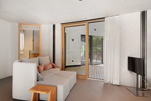 Sala de estar moderna com sofá, televisão e porta de vidro deslizante que dá para uma área externa.