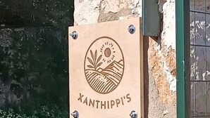 A wooden sign with a sun and landscape design, mounted on a stone wall. - Xanthippi s Traditional House in Pemonia (Apokoronas)