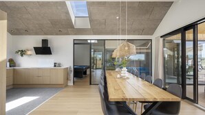 Une cuisine moderne avec des meubles en bois, une cuisinière encastrée et un coin repas comprenant une table et des chaises en bois.