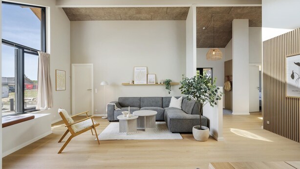 Un salon moderne avec un canapé gris, une table basse ronde et un plancher en bois.