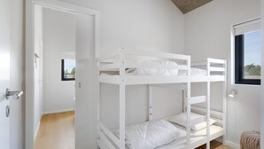 Une chambre avec un lit superposé, une porte donnant sur un couloir, une fenêtre avec vue et un petit tapis.