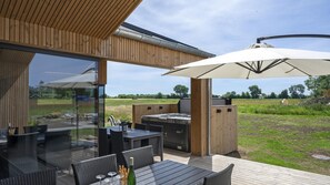An outdoor patio with a glass enclosure, wooden deck, and a barbecue area. - VillaVilla 975 - Hasmark Strand, Fyn og øer (Otterup)