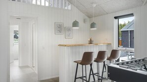 A modern kitchen with a bar area, featuring pendant lights, a wooden countertop, and bar stools. - VillaVilla 966 - Marielyst, Lolland/Falster/møn (Idestrup)