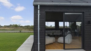 A modern house with a glass door leading to an outdoor seating area. - VillaVilla 966 - Marielyst, Lolland/Falster/møn (Idestrup)
