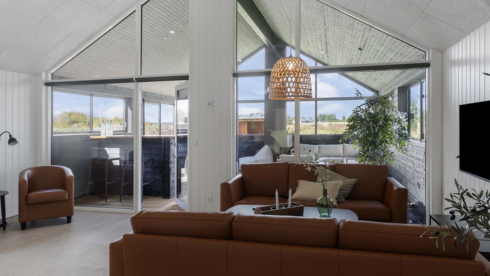 A modern living room with a leather sofa, a coffee table, and a hanging light fixture.