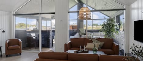A modern living room with a leather sofa, a coffee table, and a hanging light fixture.
